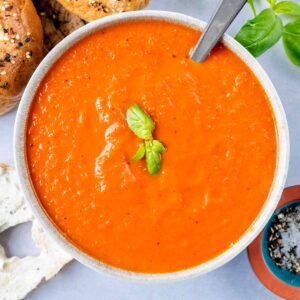 A bowl of easy tomato soup with two small basil leaves on top.