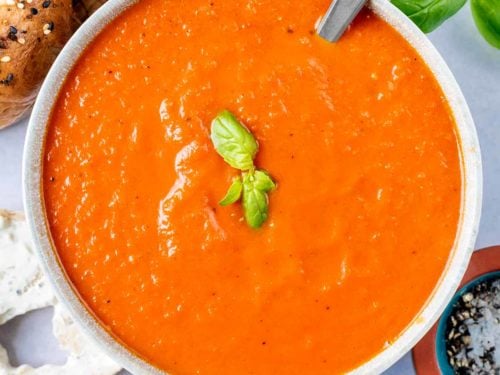 A bowl of easy tomato soup with two small basil leaves on top.