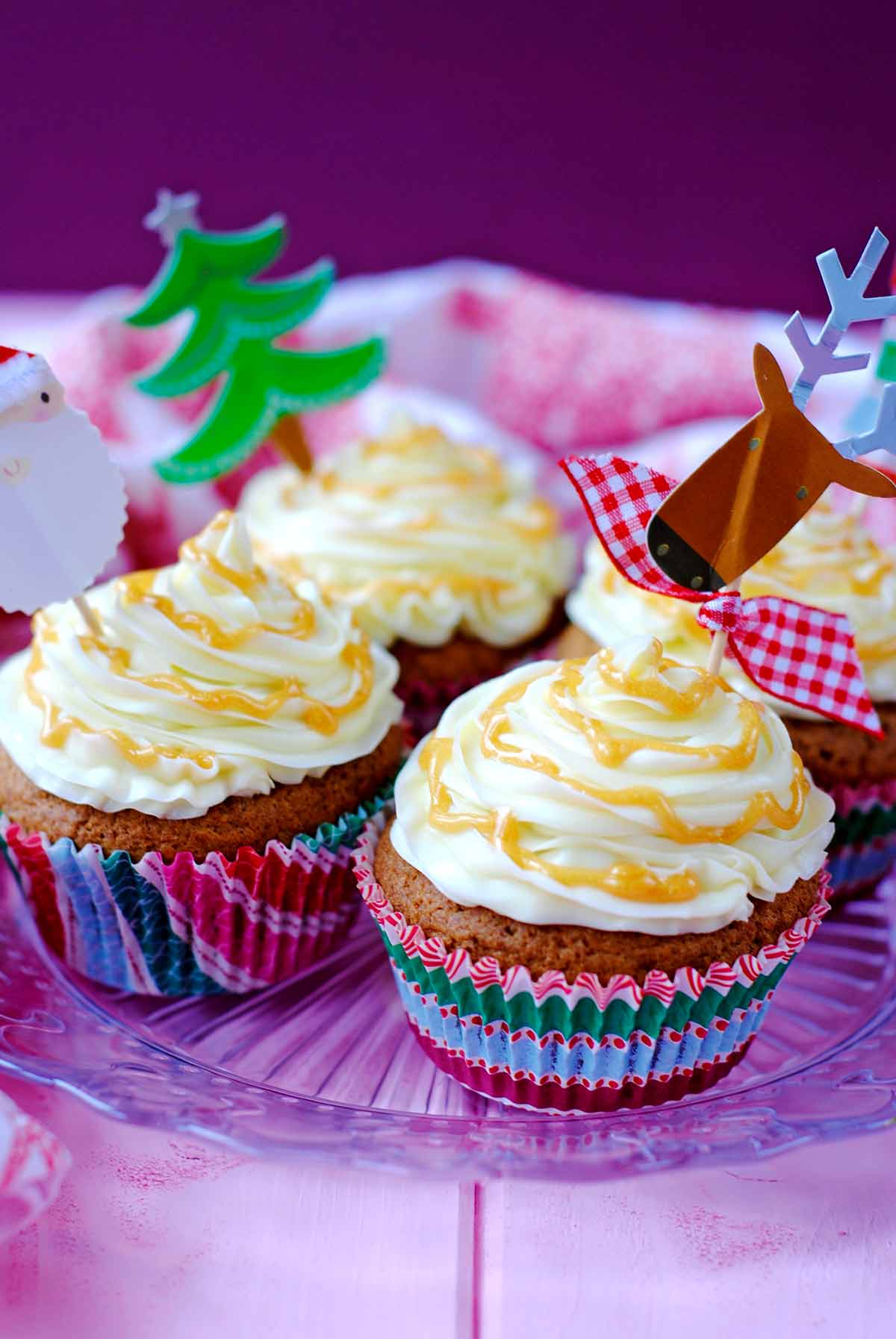 Four cupcakes decorated with Christmas designs.
