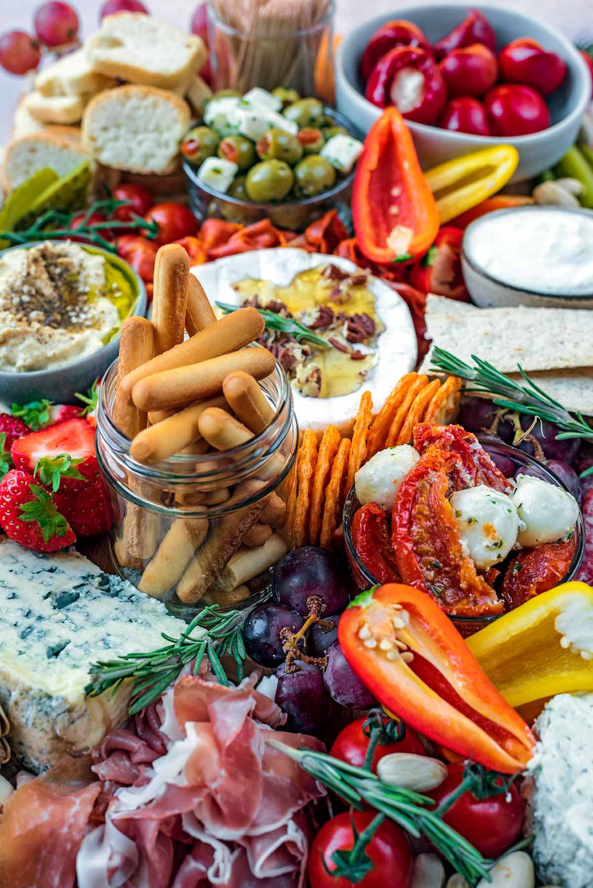 A small jar of bread sticks in the middle of a grazing platter.