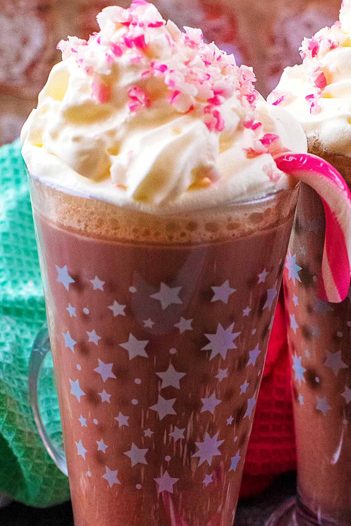 Crushed candy canes sprinkled over whipped cream on top of a glass of hot chocolate.