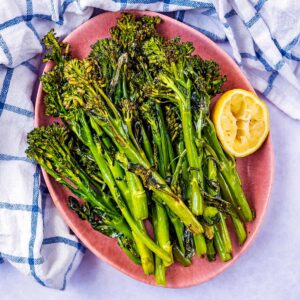 Roasted tenderstem broccoli and a lemon half on an oval plate.