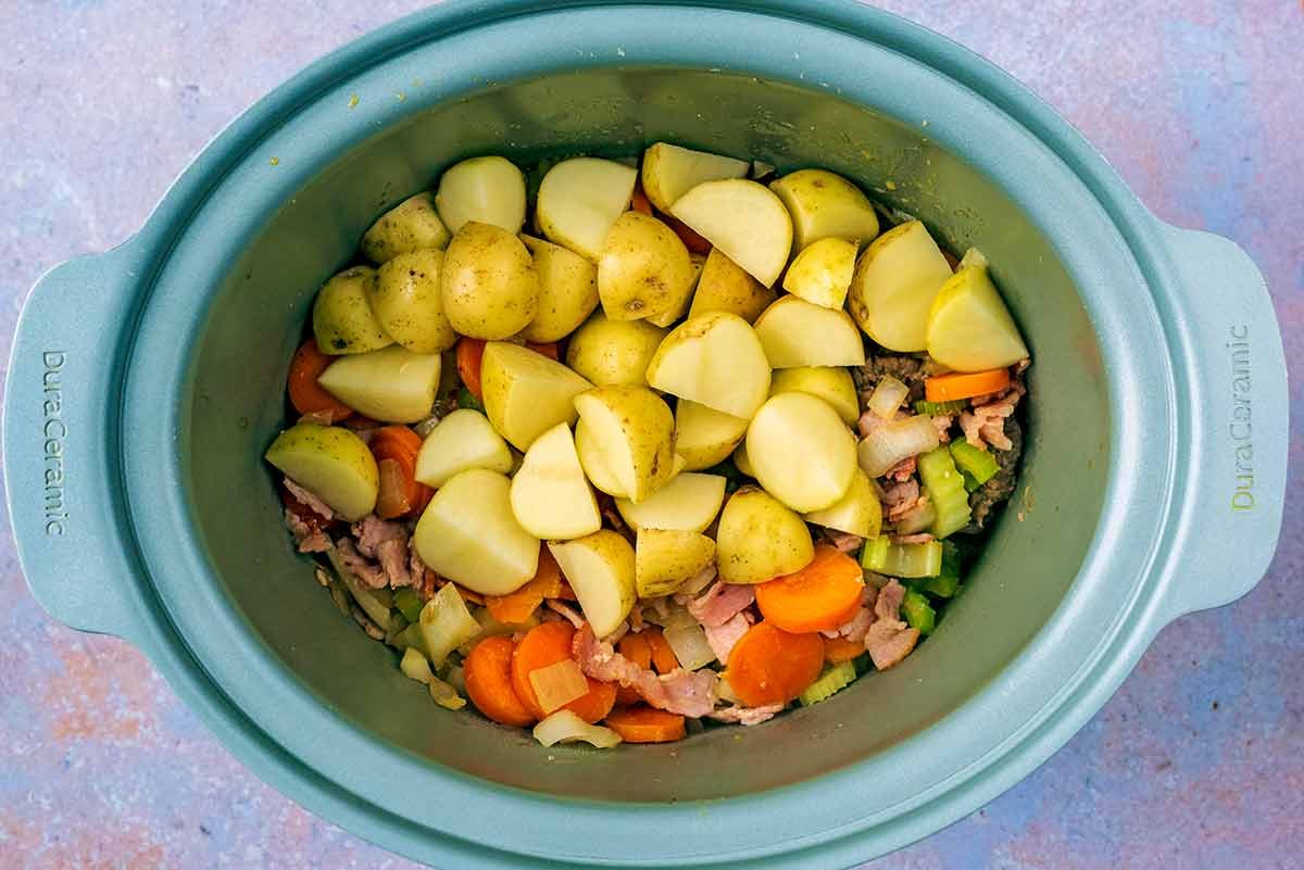 Beef, vegetables and potatoes in a slow cooker bowl.