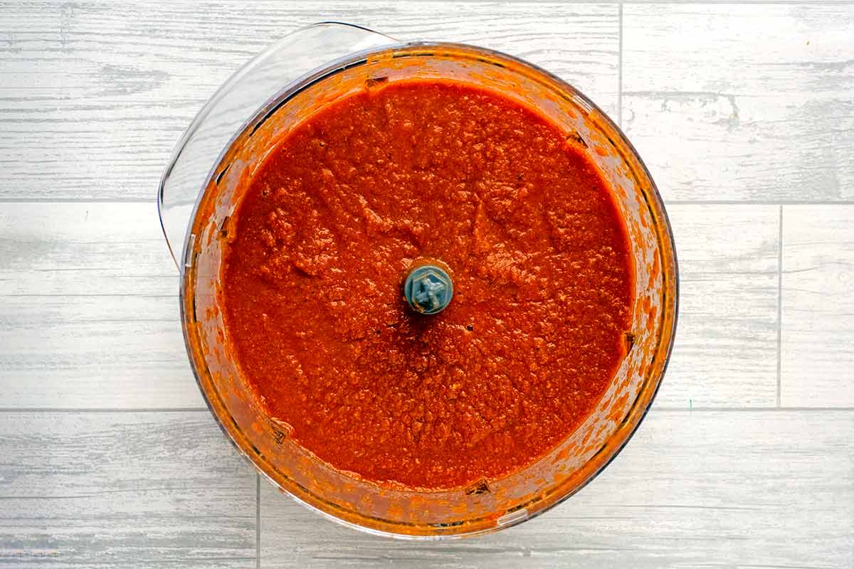 A food processor containing a blended tomato sauce.
