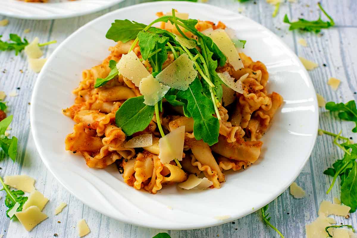 Pasta, in Slow Cooker Vegetable Pasta Sauce, topped with arugula and parmesan.