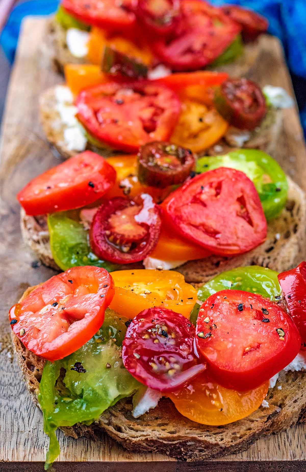 Sliced tomatoes on toast on a serving board.