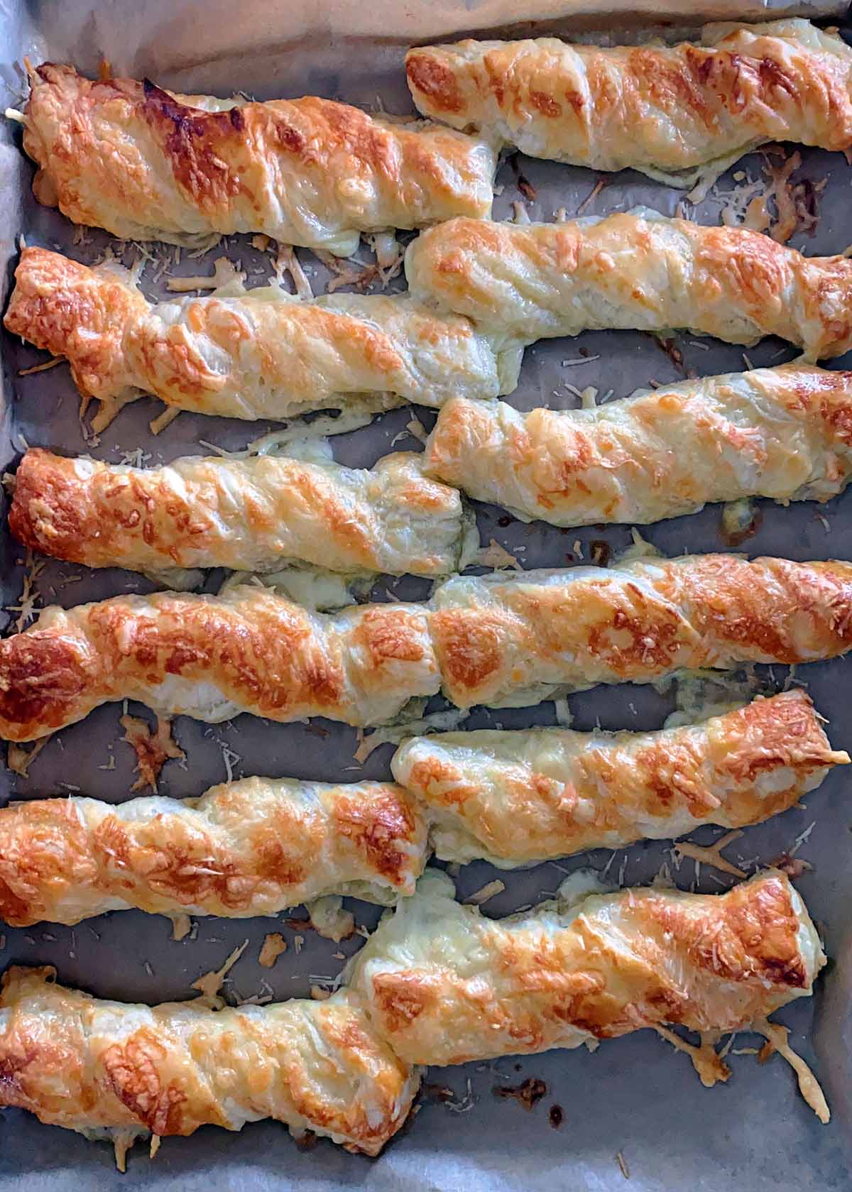 Cooked cheese straws on a baking tray.