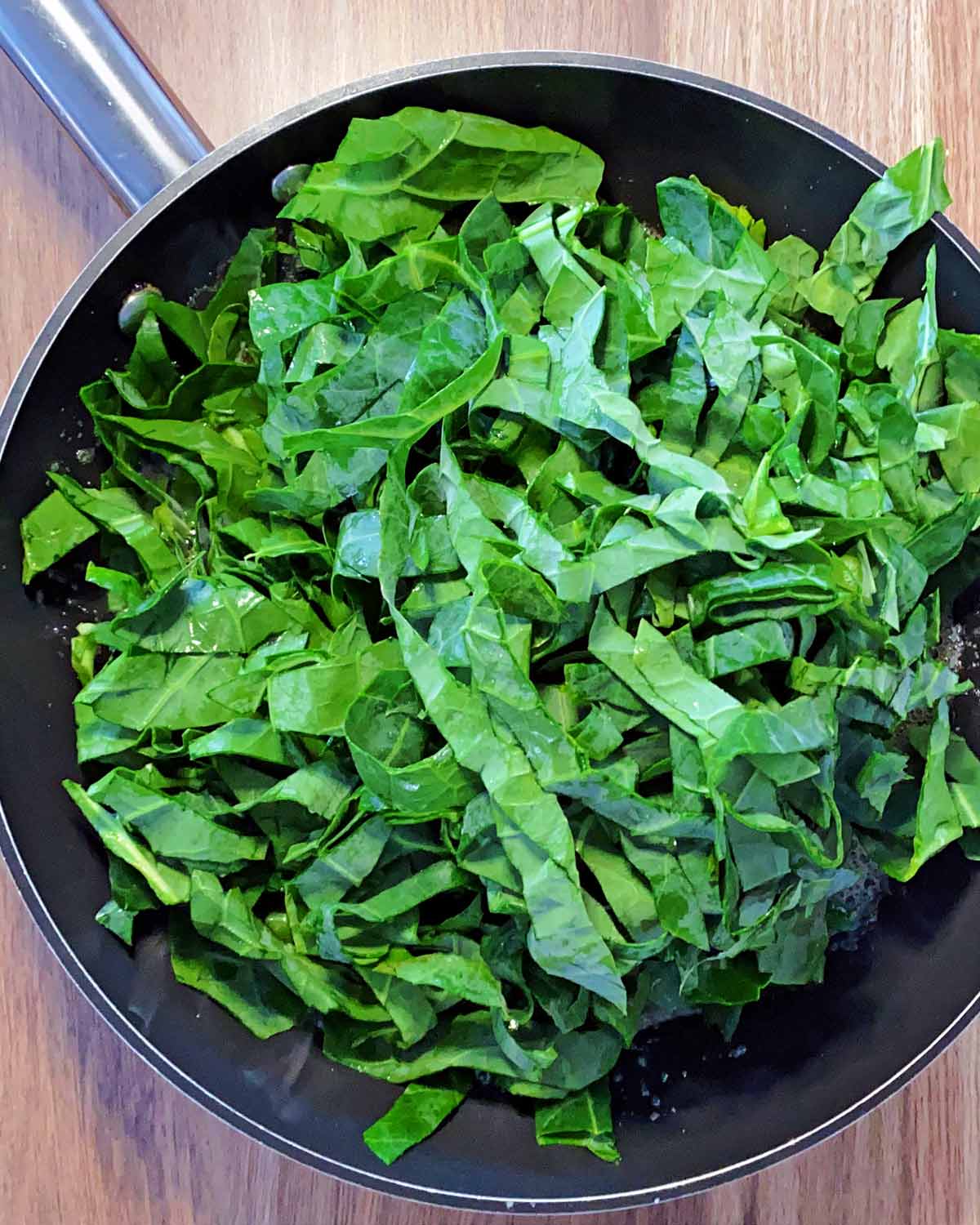 Shredded spring greens added to the pan.