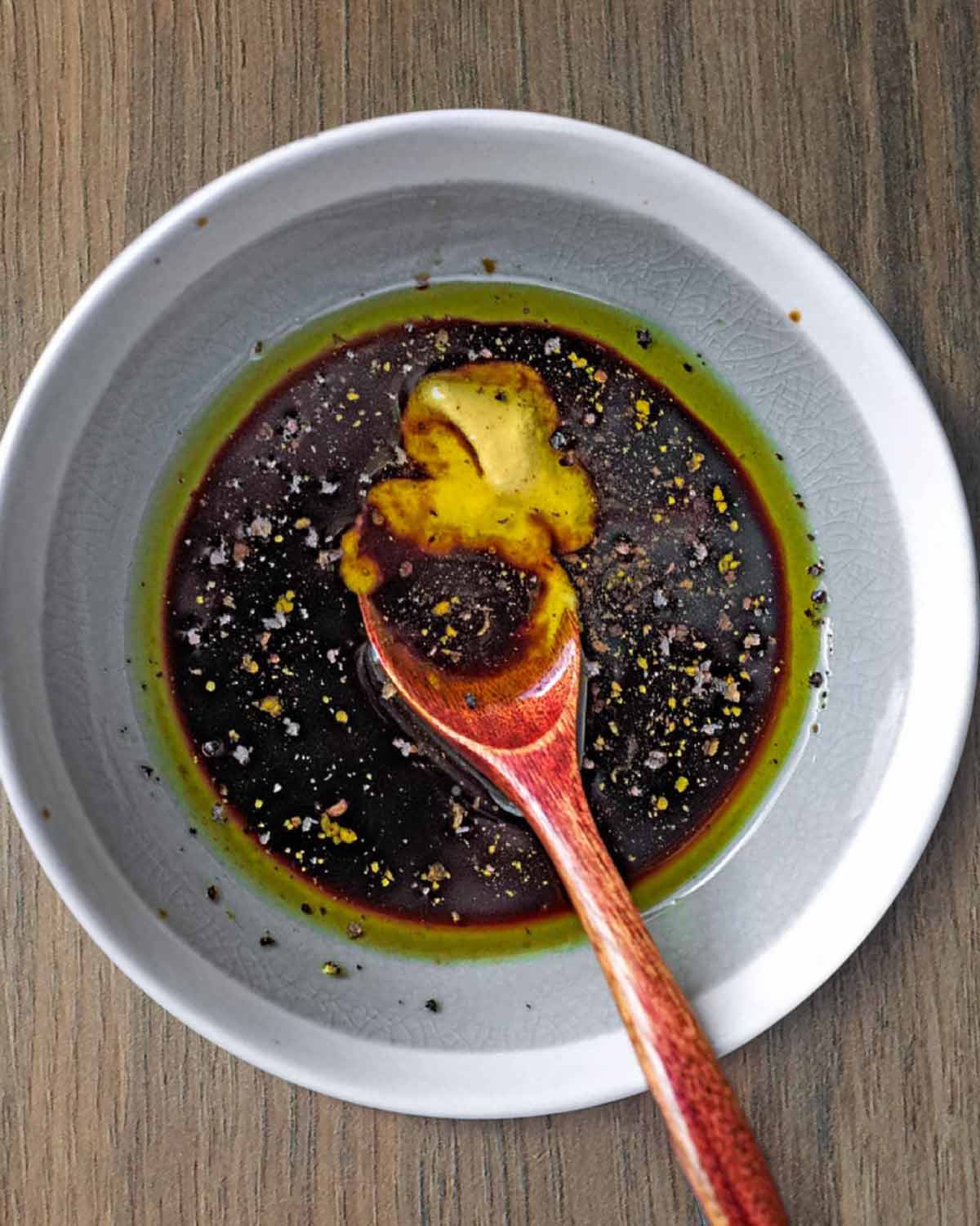 A bowl of salad dressing mado from oil, balsamic vinegar and mustard.