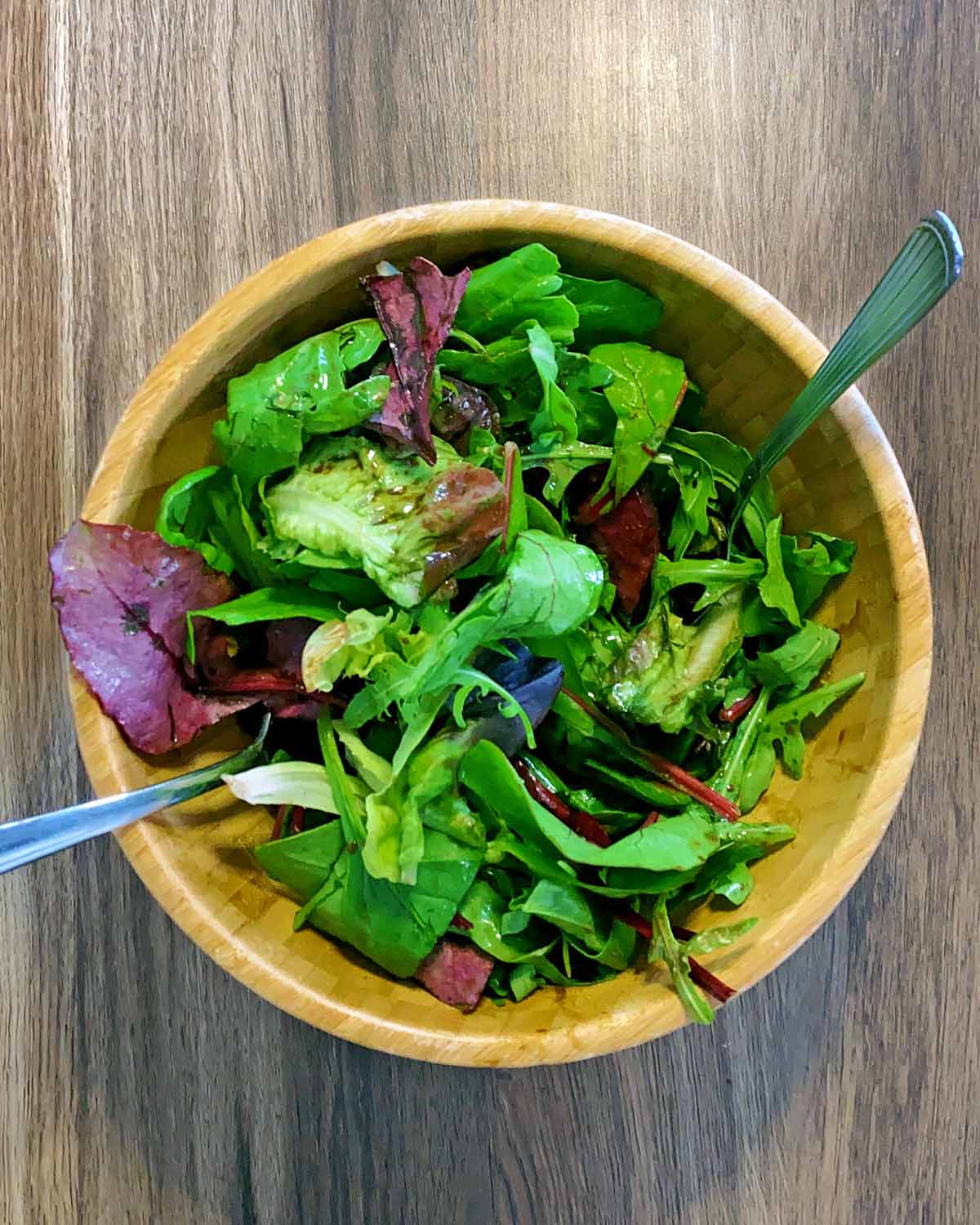 Lettuce in a bowl with dressing added.