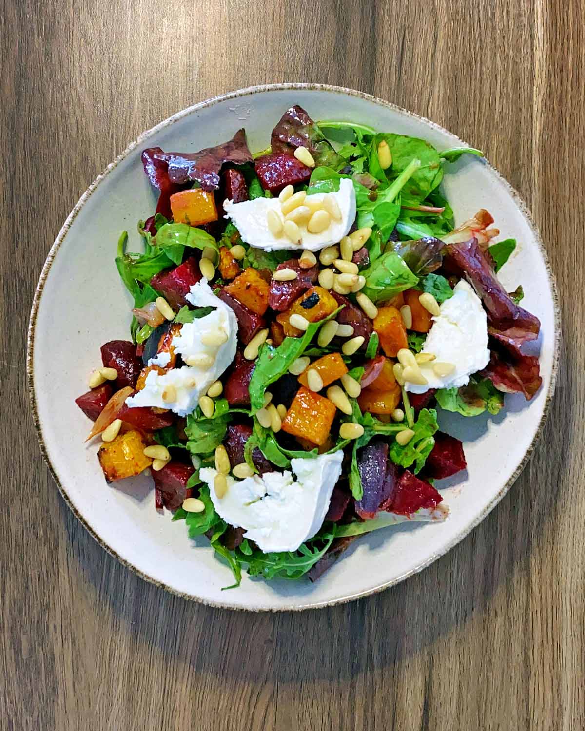 The salad on a bowl with goat's cheese and pine nuts added.