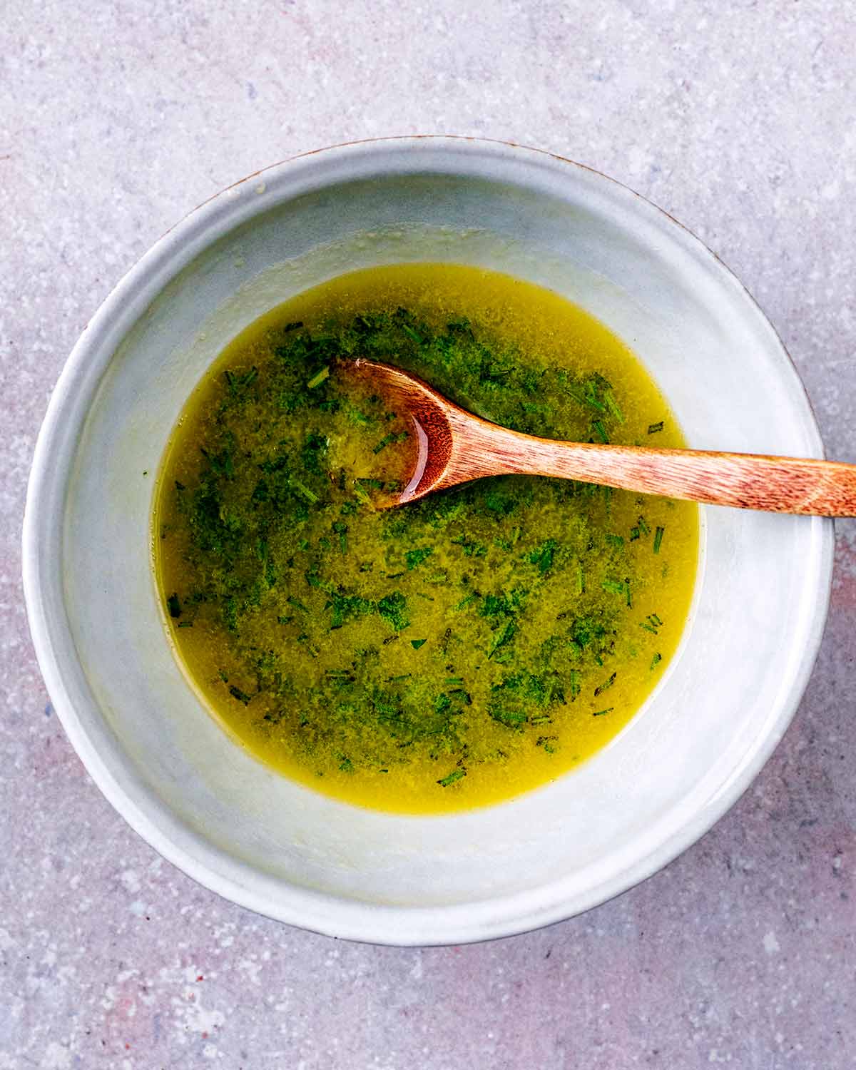 Melted butter and chopped herbs in a bowl.