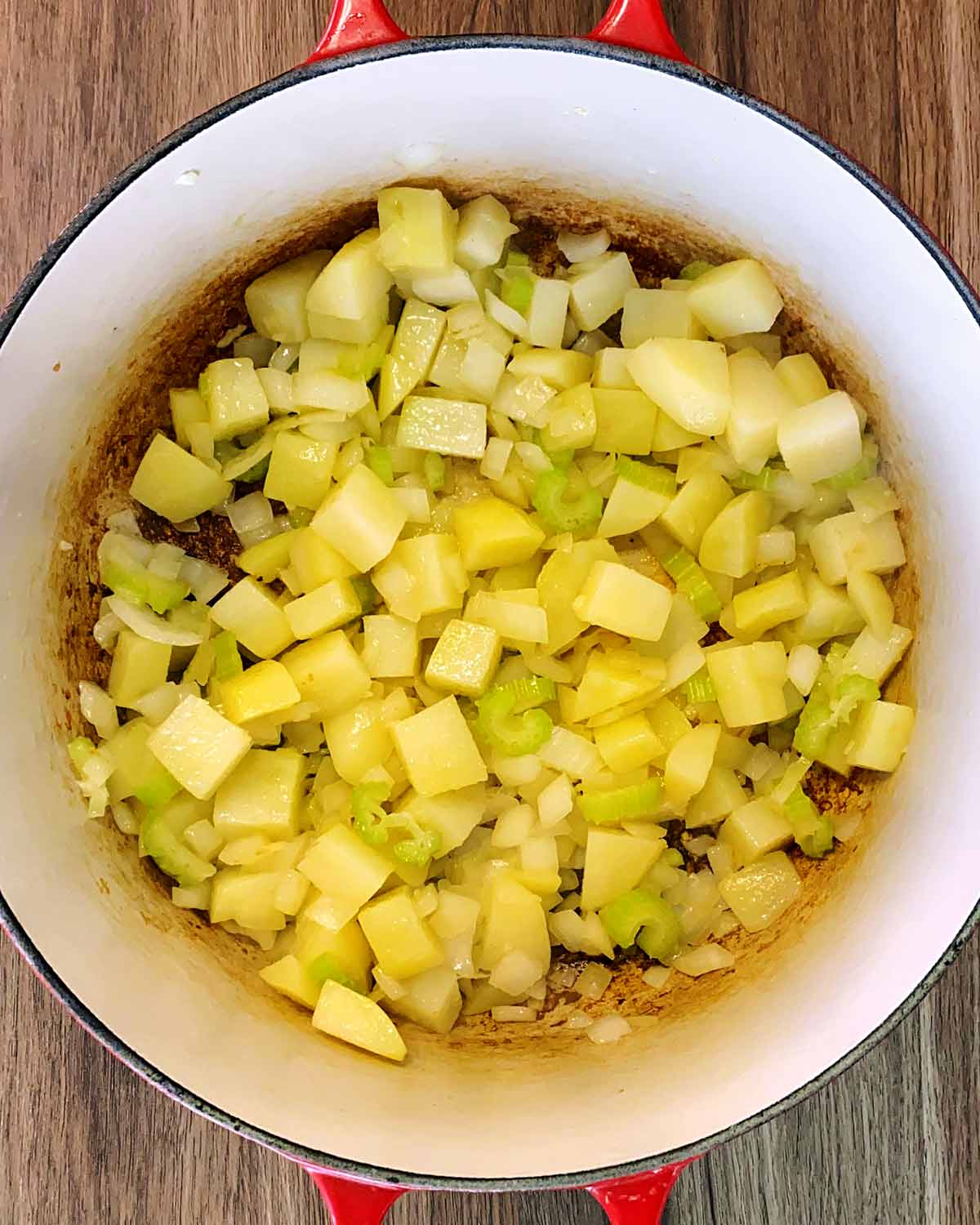 Chunks of potato, onion and celery cooking in a large pan.