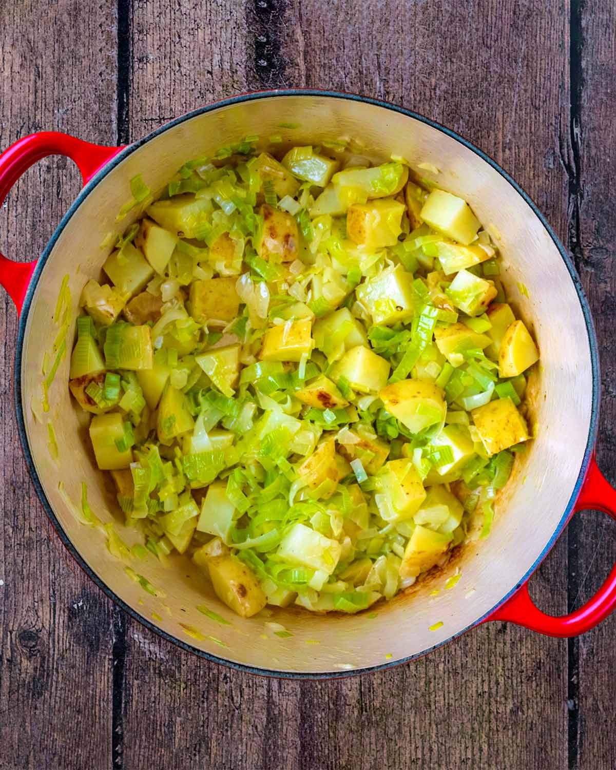 Chopped vegetables in a large red cooking pot.