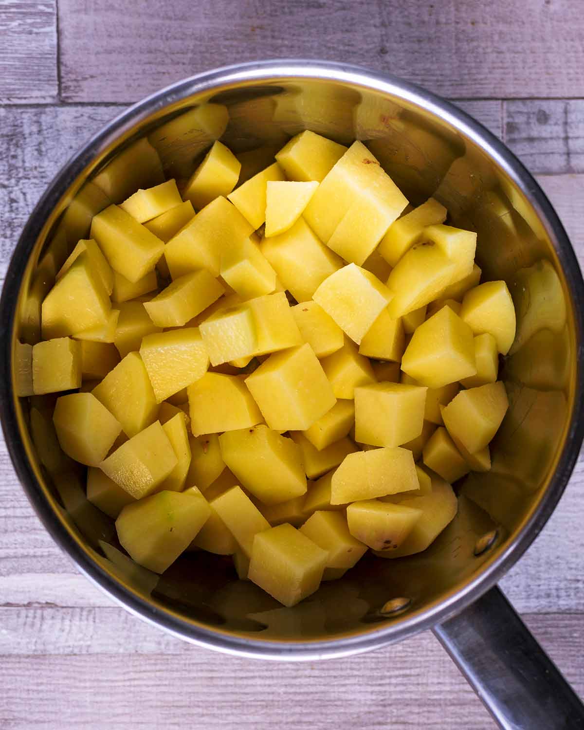 A saucepan containing peeled and chopped potatoes.
