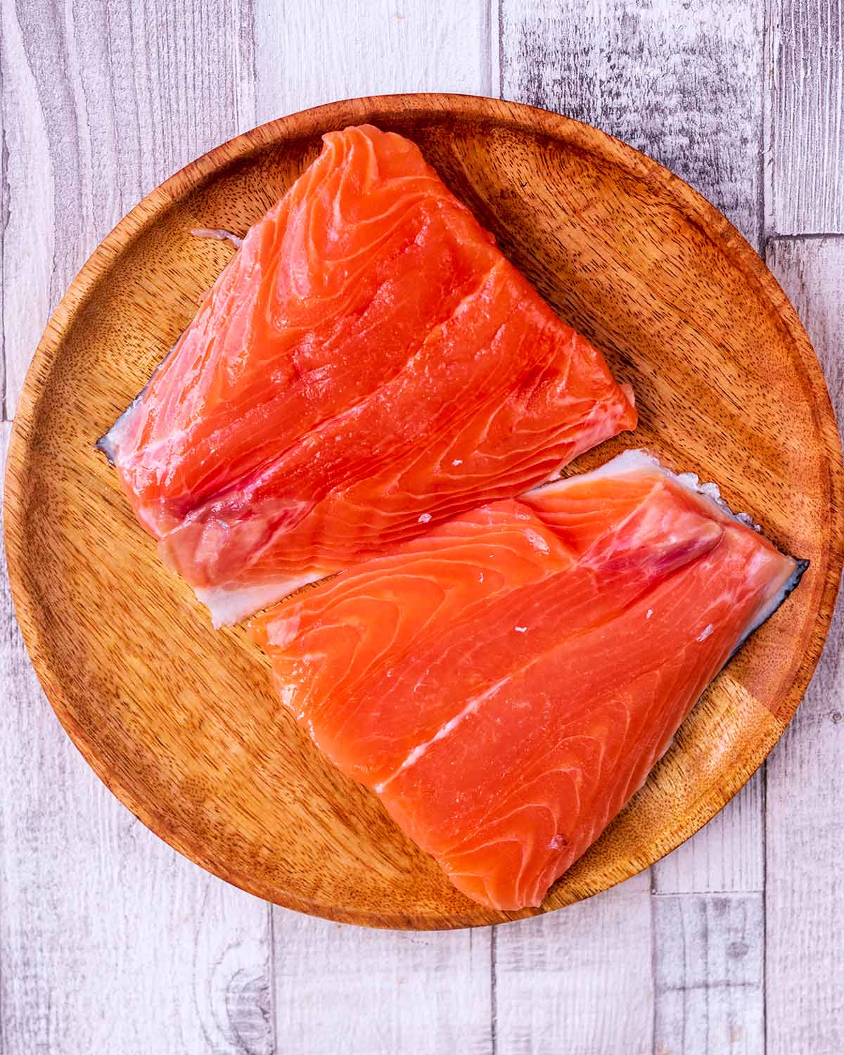Two raw salmon fillets on a plate.