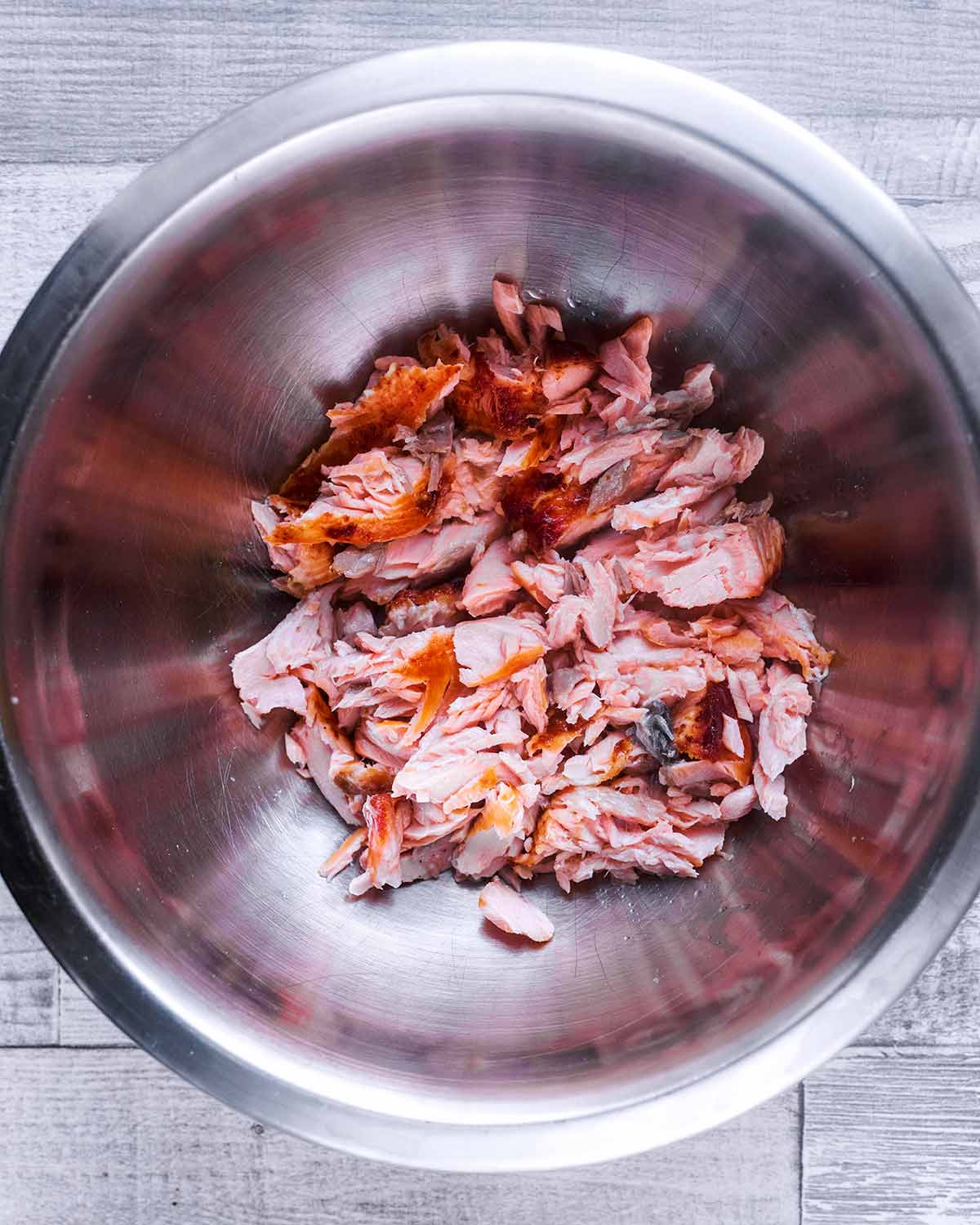 Flaked salmon in a large mixing bowl.