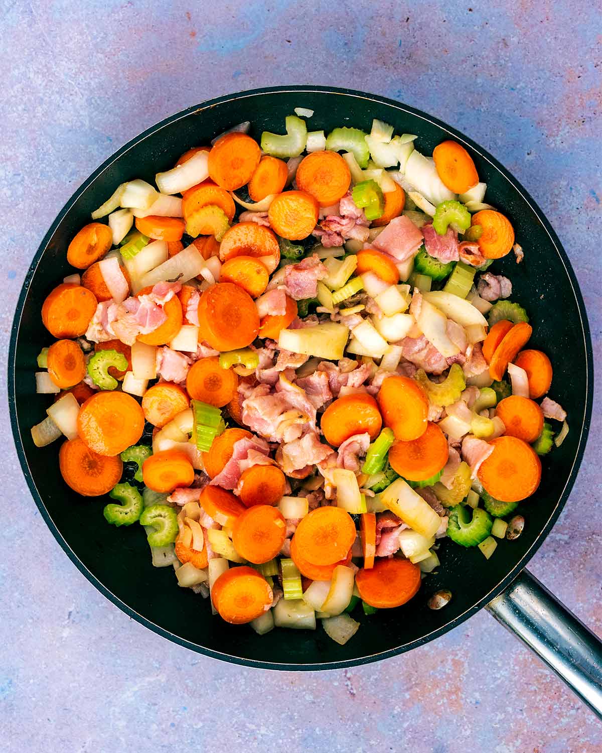 Chopped bacon and vegetables cooking in the pan.