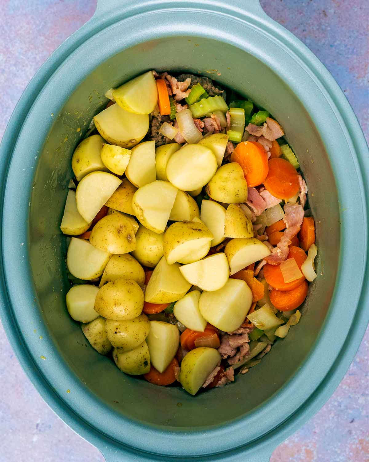 Beef, vegetables and potatoes in a slow cooker bowl.