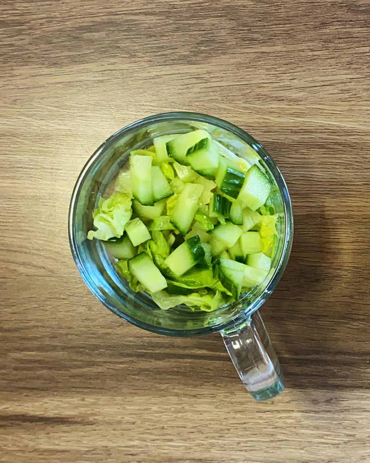 Chopped lettuce and cucumber in a serving glass.