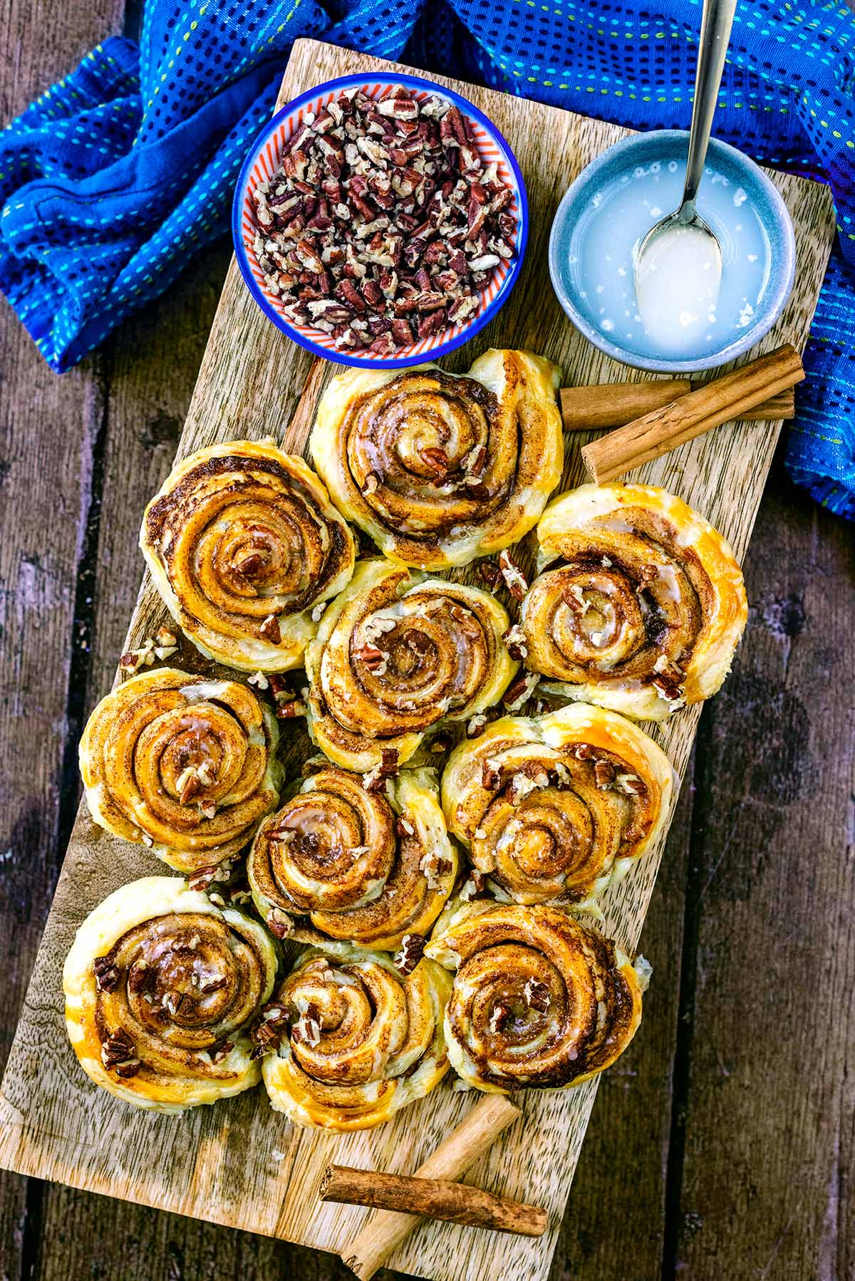 A serving board covered in cinnamon swirls, pecans and icing.