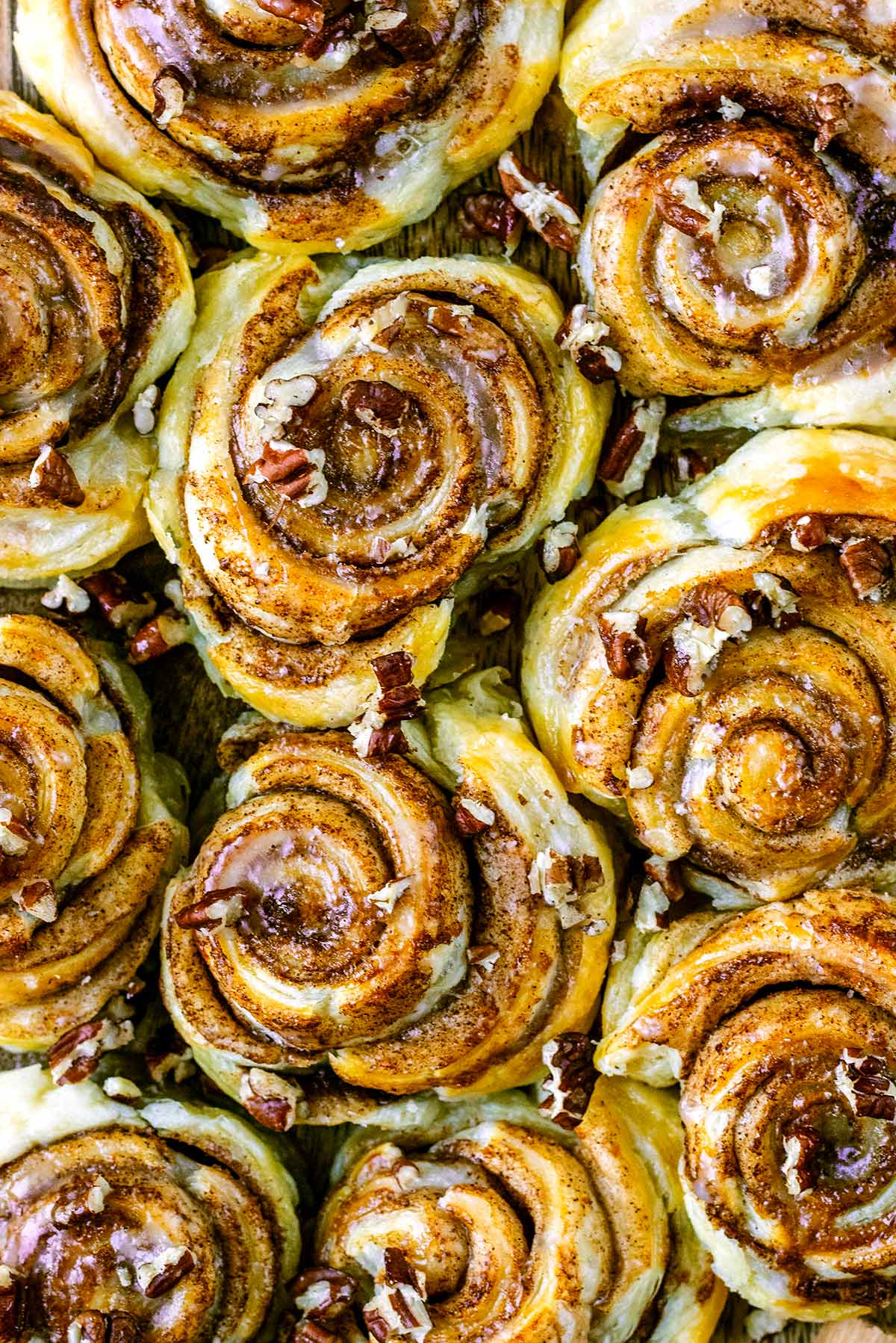 Cooked cinnamon swirls covered in icing and chopped pecans.