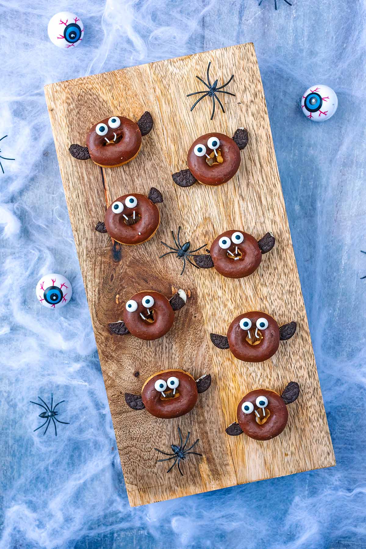 A wooden board with eight mini doughnuts decorated like bats.