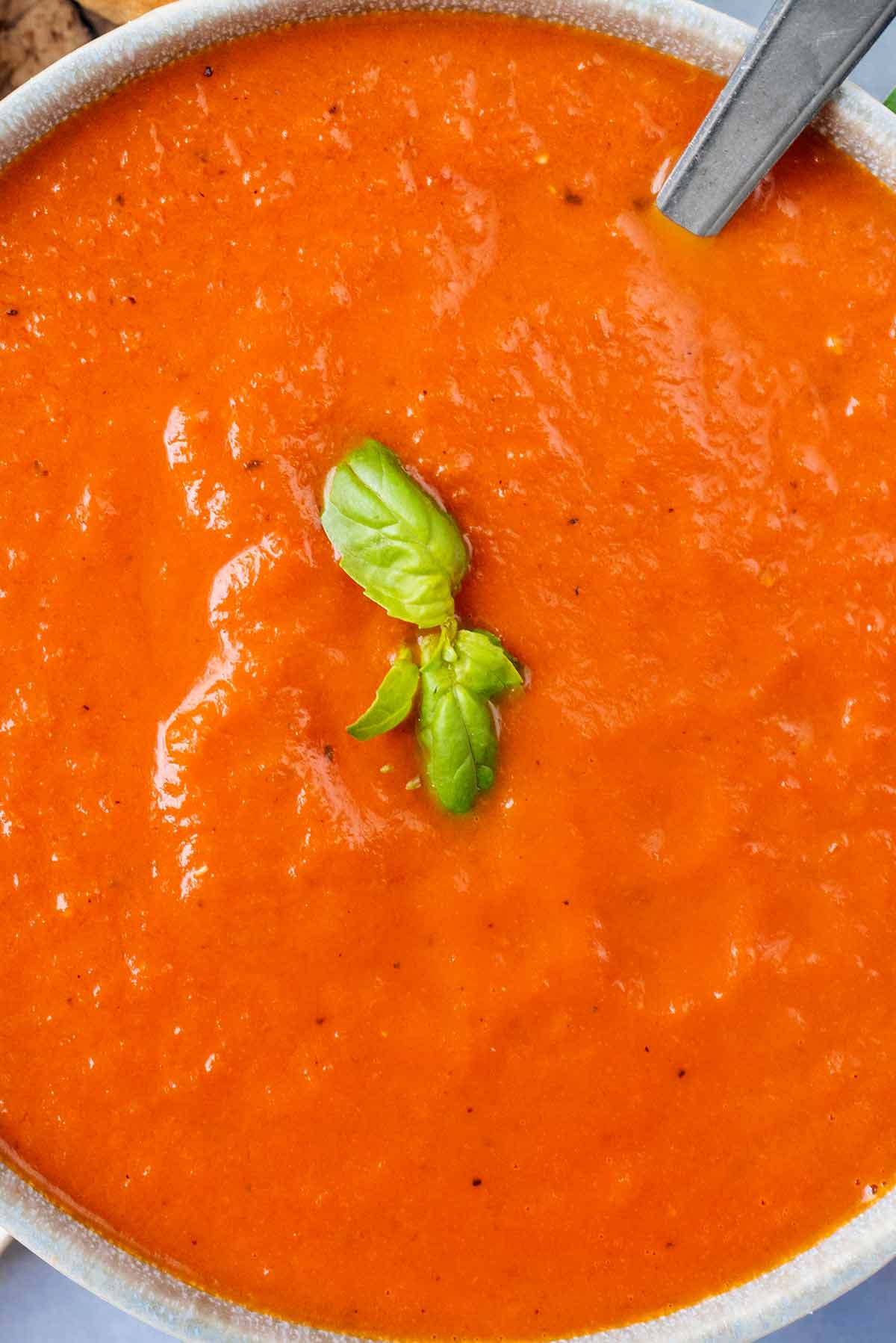 Four small basil leaves on top of some tomato soup.