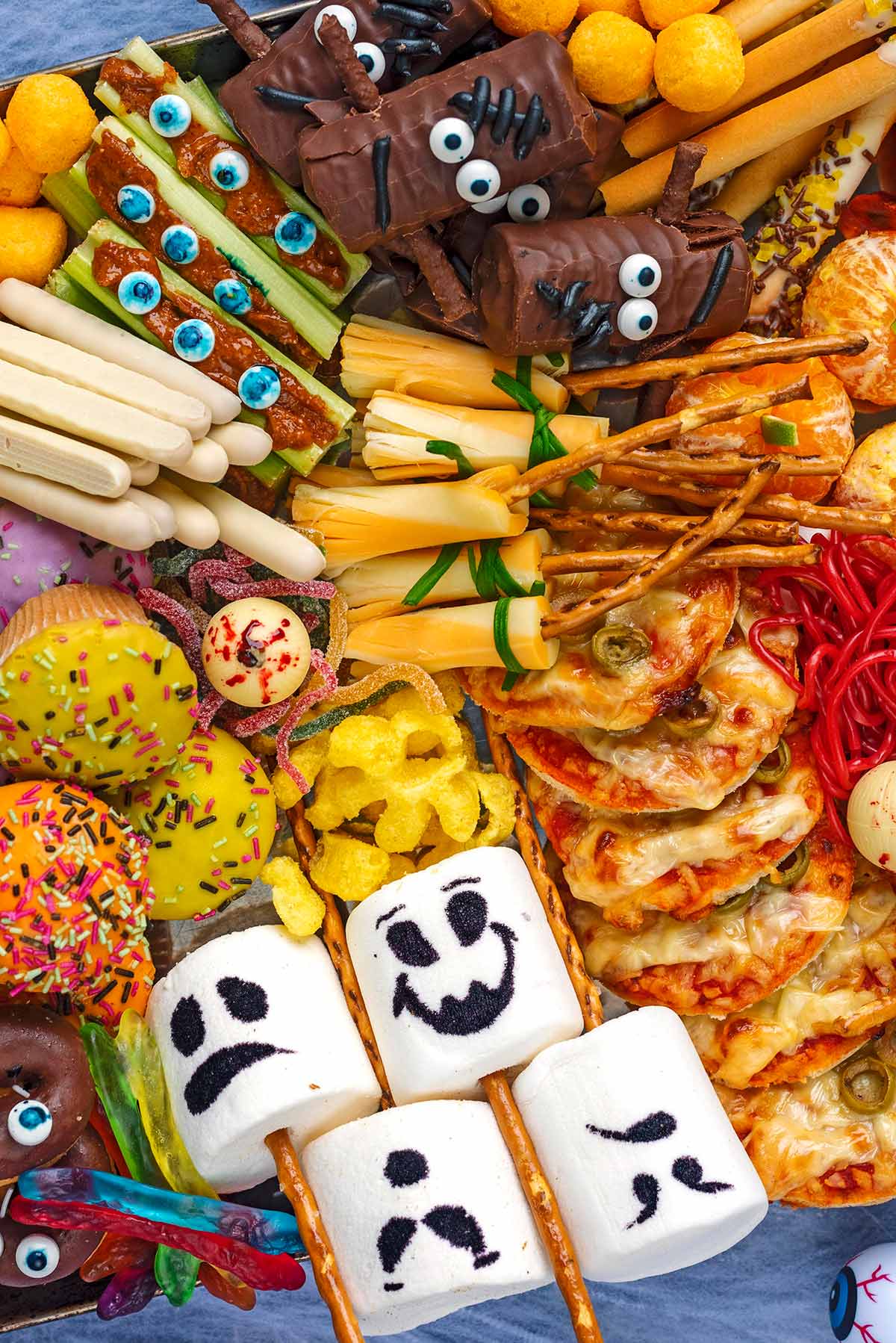 Various sweet treats set out on a platter, including marshmallow ghosts, cheese broomsticks and chocolate eyeballs.