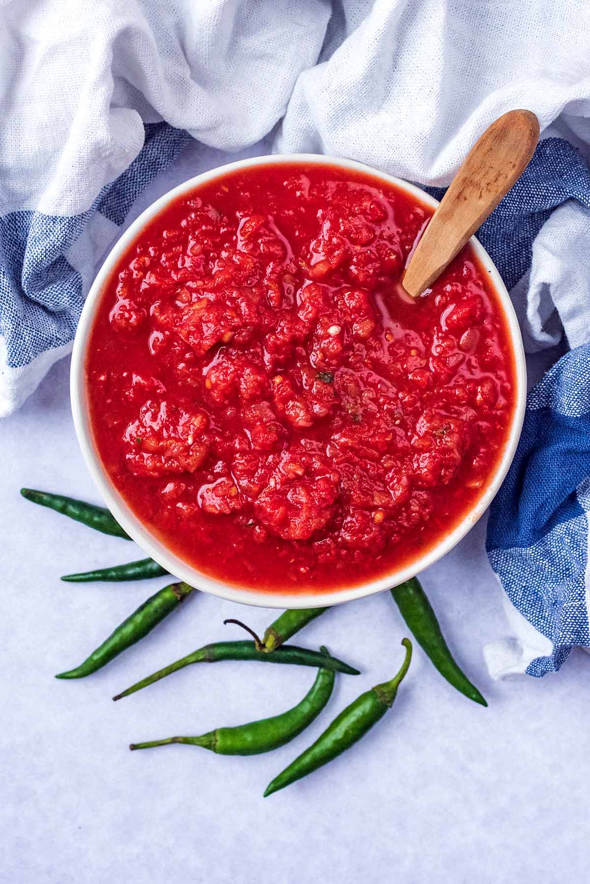 A bowl of chilli sauce next to some bird's eye chillies.