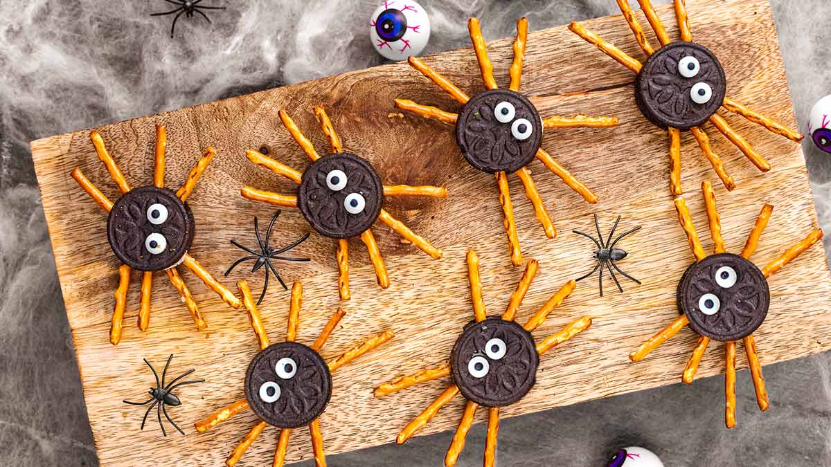 Eight Oreo Sppiders on a wooden board surrounded by cobwebs.