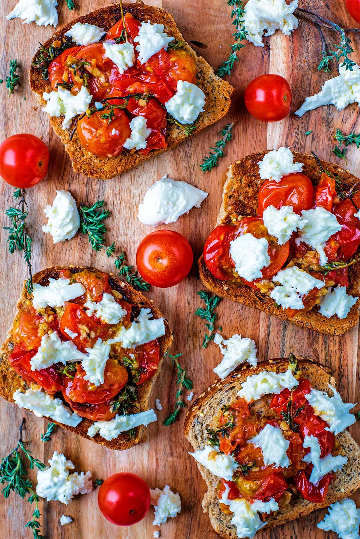 Roasted Cherry Tomatoes on toast with chunks of white cheese and sprigs of thyme.