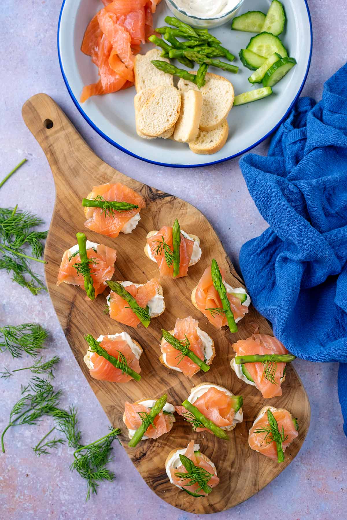 A wooden serving board with salmon canapes on it.