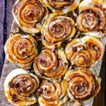 Ten cinnamon swirls on a wooden board.