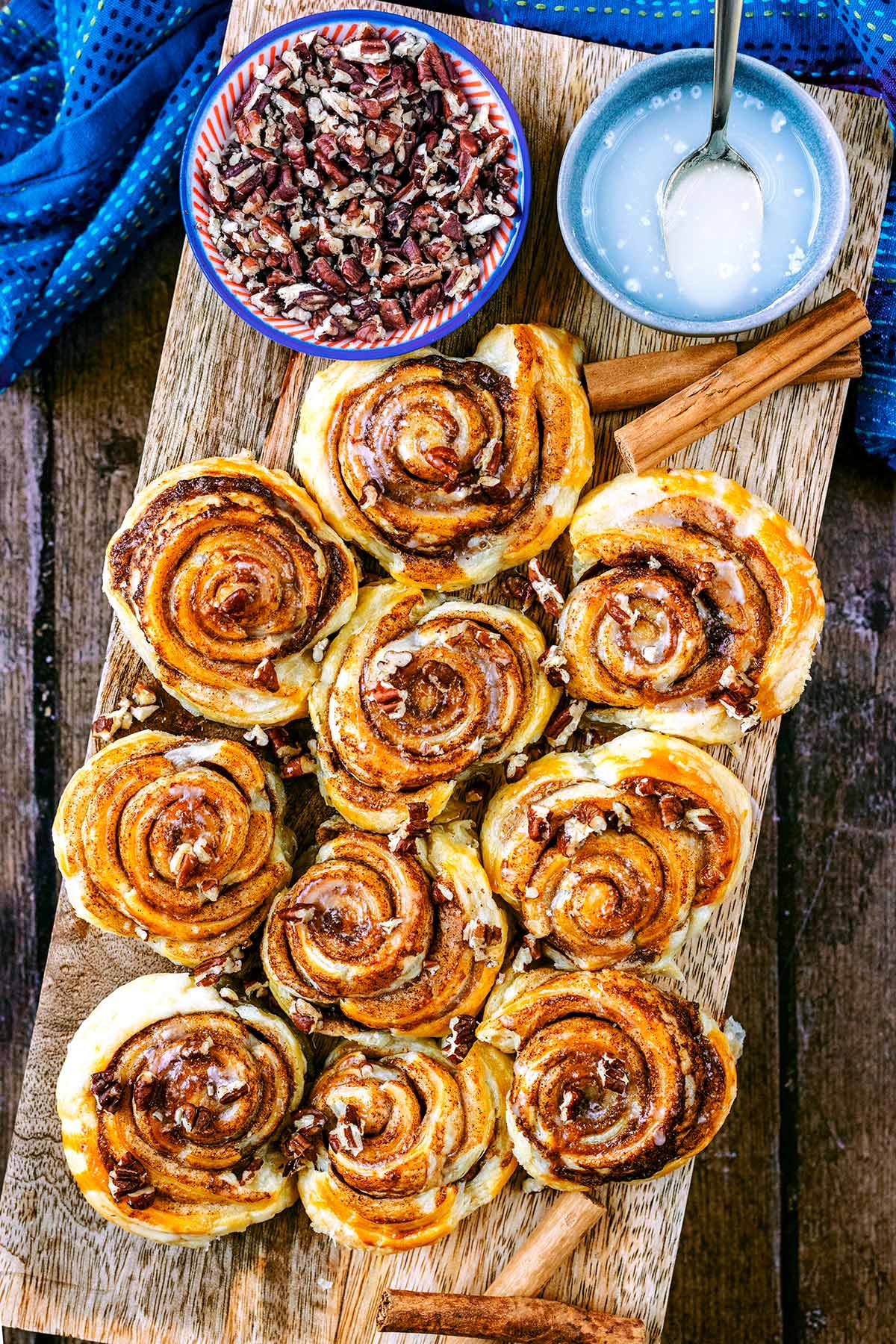 A serving board covered in cinnamon swirls, pecans and icing.