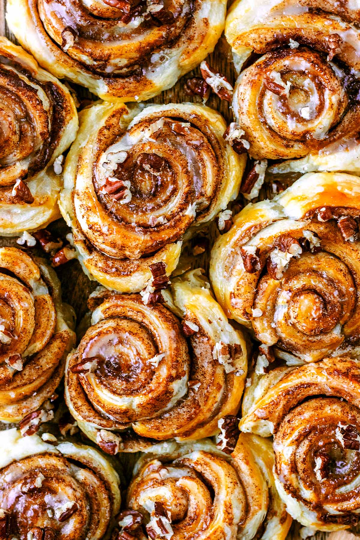 Cooked cinnamon swirls covered in icing and chopped pecans.