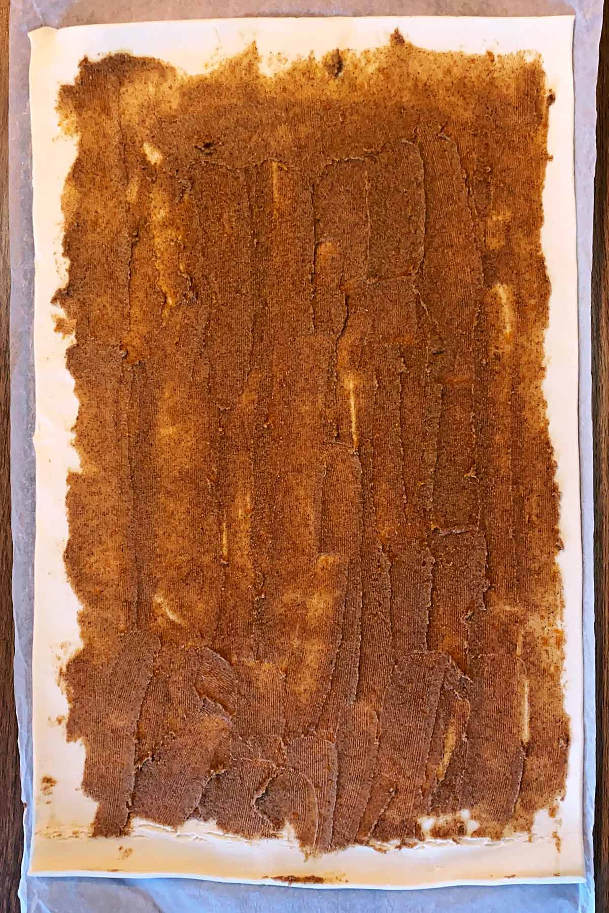 Cinnamon paste spread over a sheet of puff pastry.