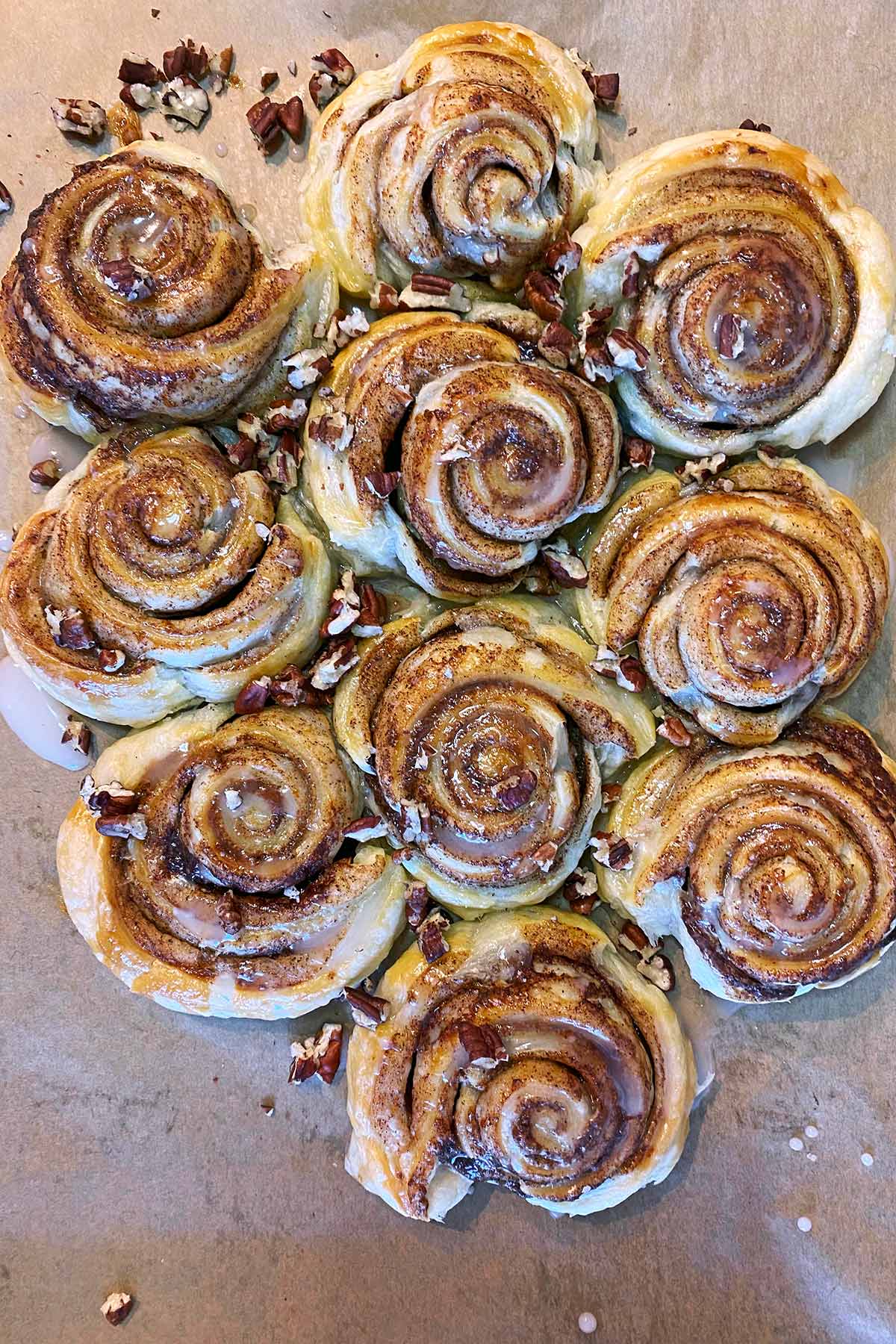 Ten cooked cinnamon swirls topped with icing and chopped pecans.