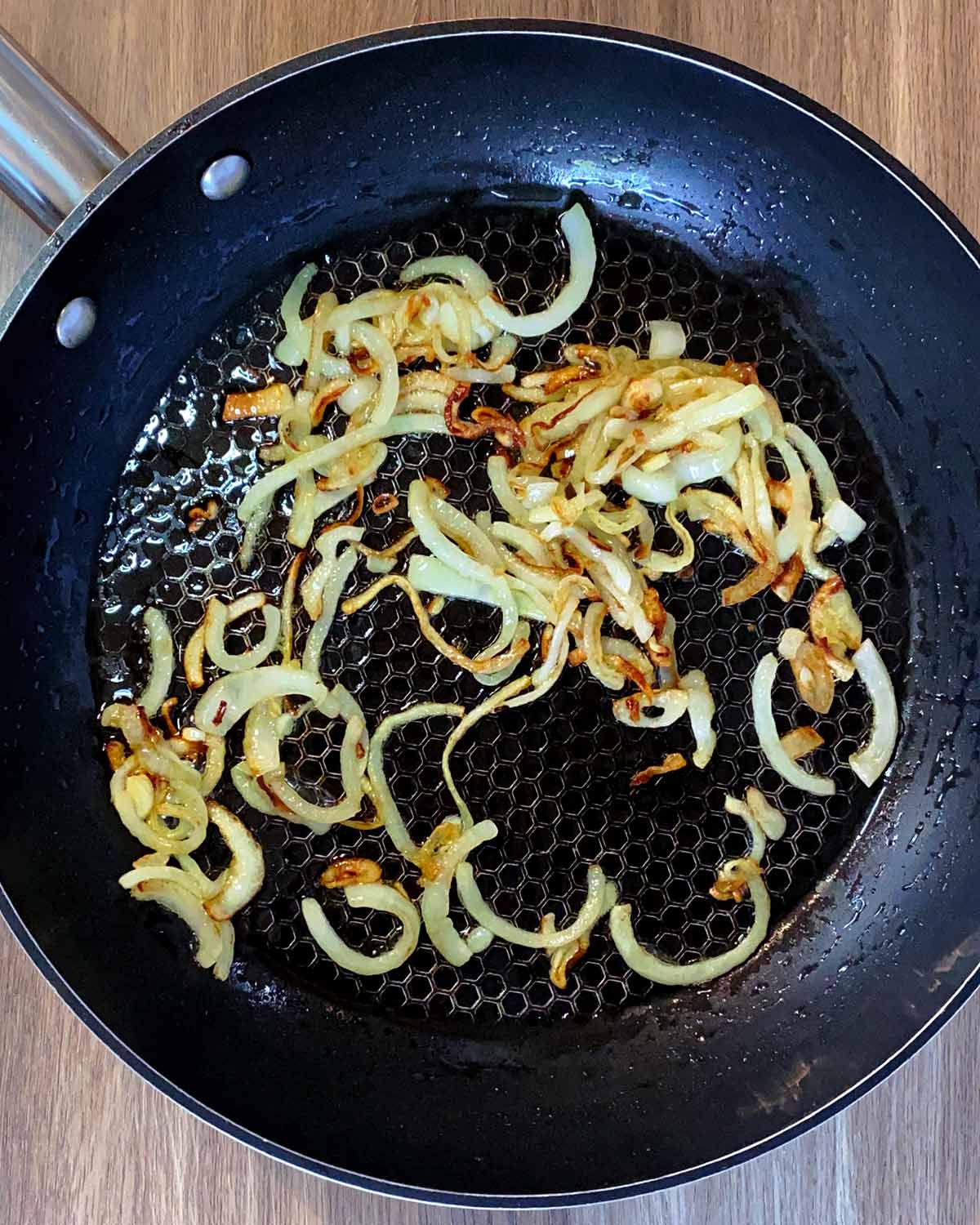 Sliced onions cooking in a frying pan.