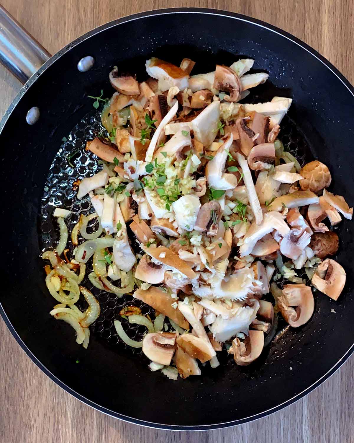 Sliced mushrooms and thyme leaves added to the pan.