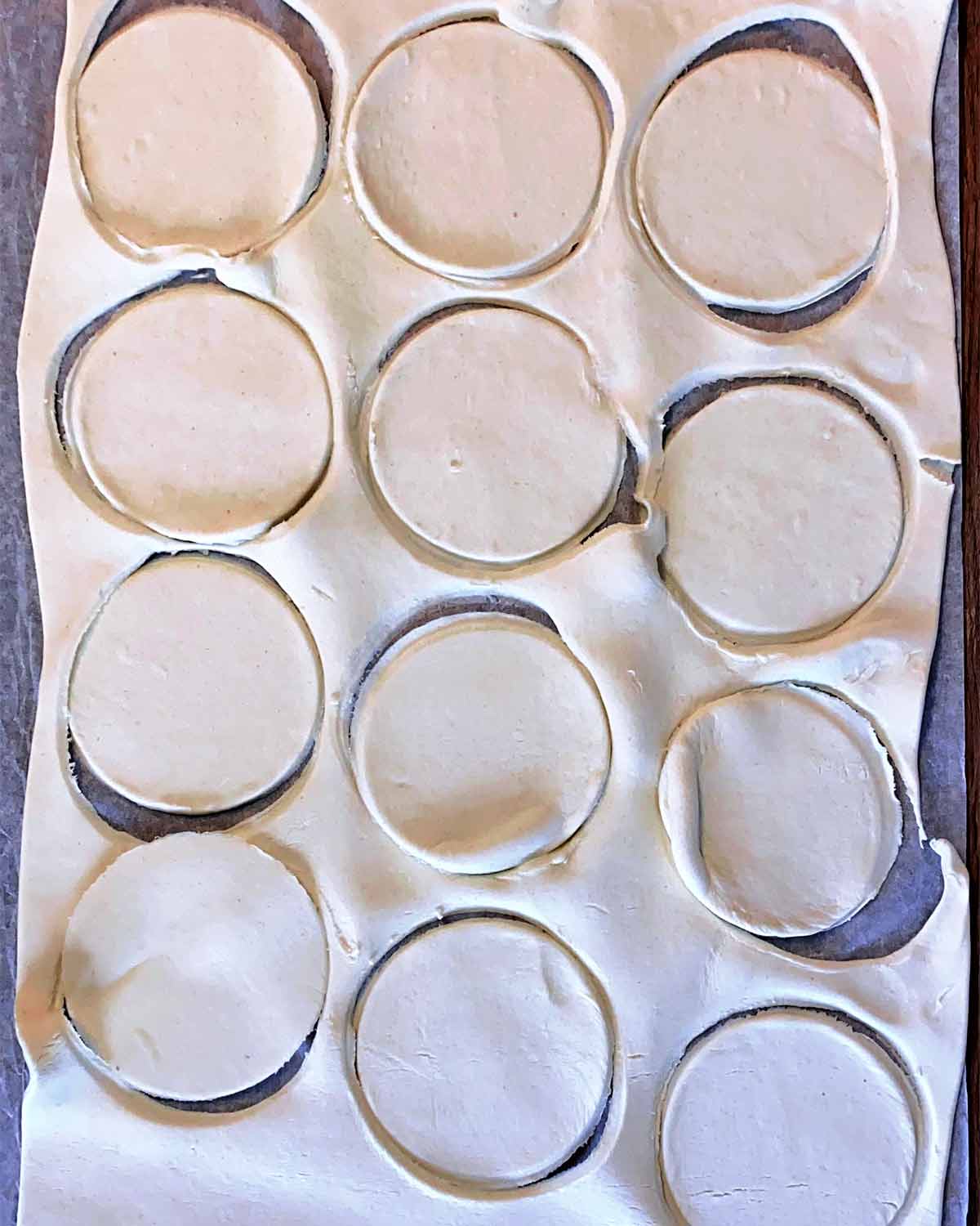 A sheet of pastry with discs cut out of it.