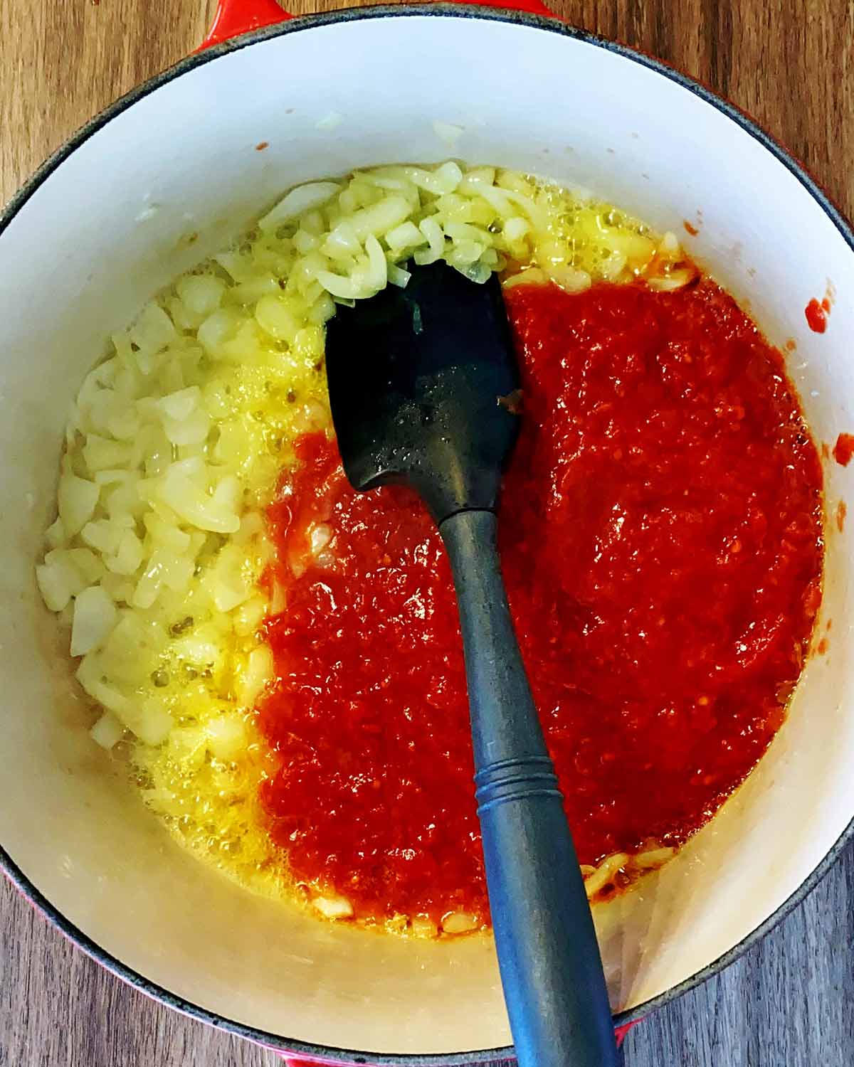 Chopped tomatoes added to the onion in the oan.