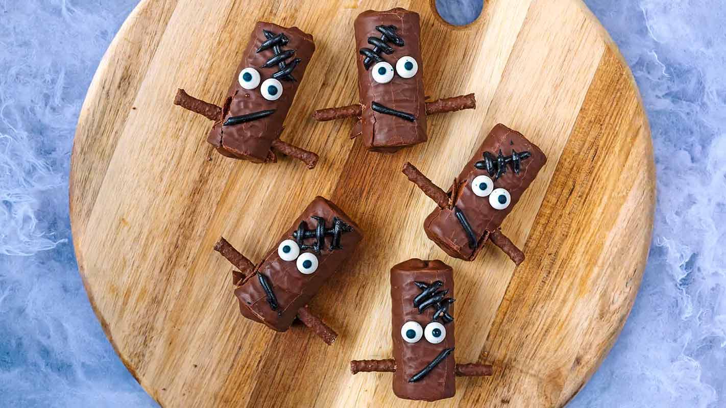 Four Frankenstein mini rolls on a wooden board.