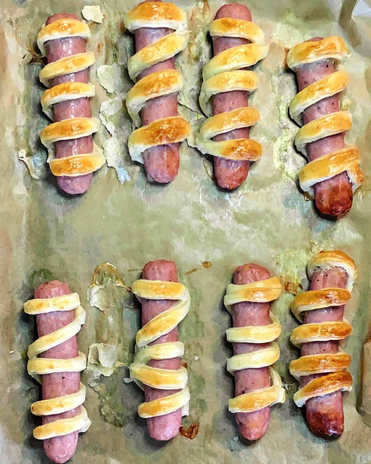 The pastry wrapped sausages now cooked on the baking tray.