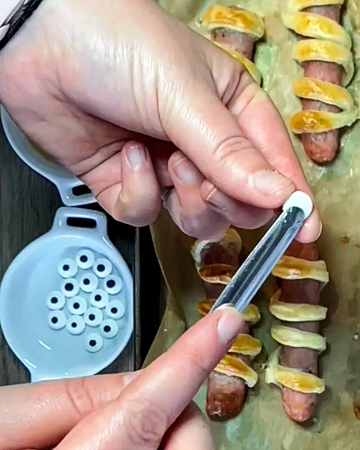 Hands putting a dot of honey onto the back of an edible eye.