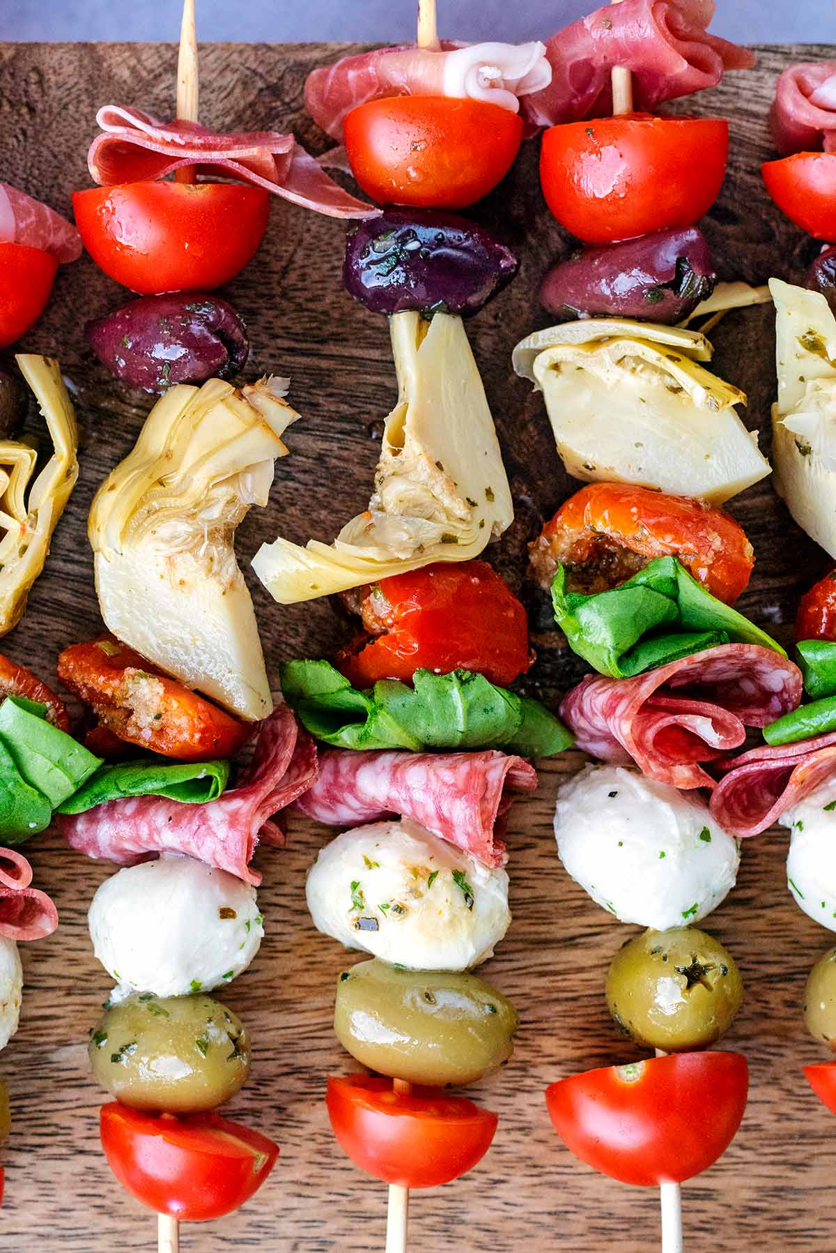 A selection of meats, cheese and vegetables on wooden skewers.