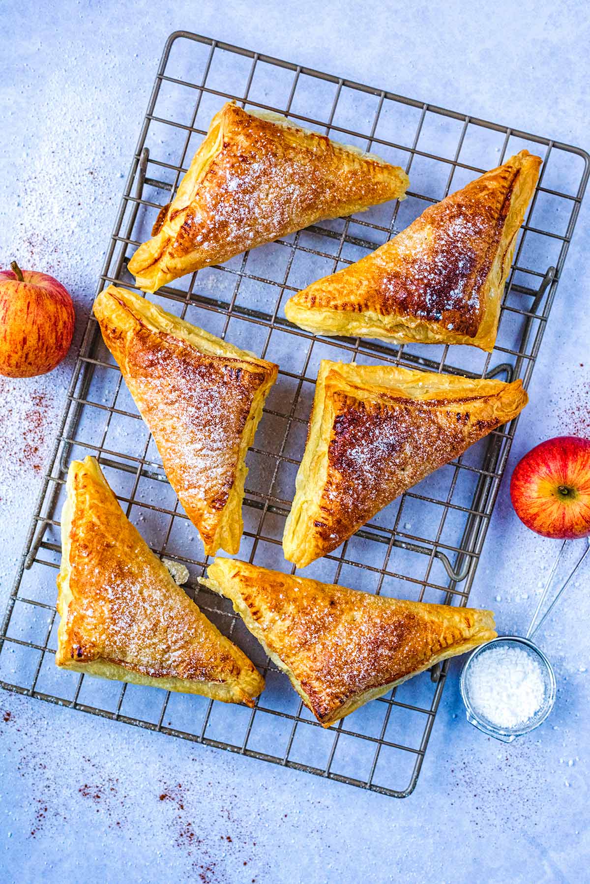 Six apple turnovers on a wire cooling rack.