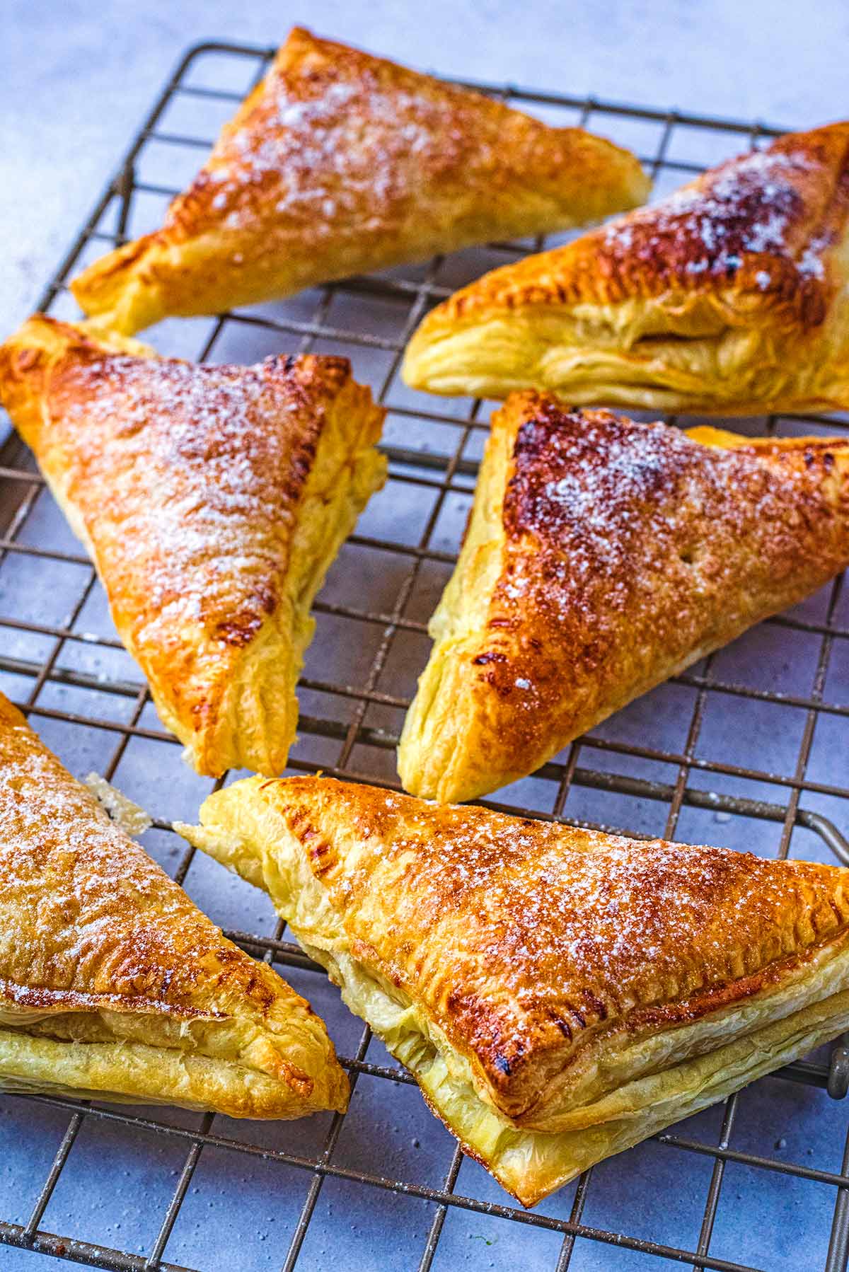 Puff pastry apple turnovers on a cooking rack.