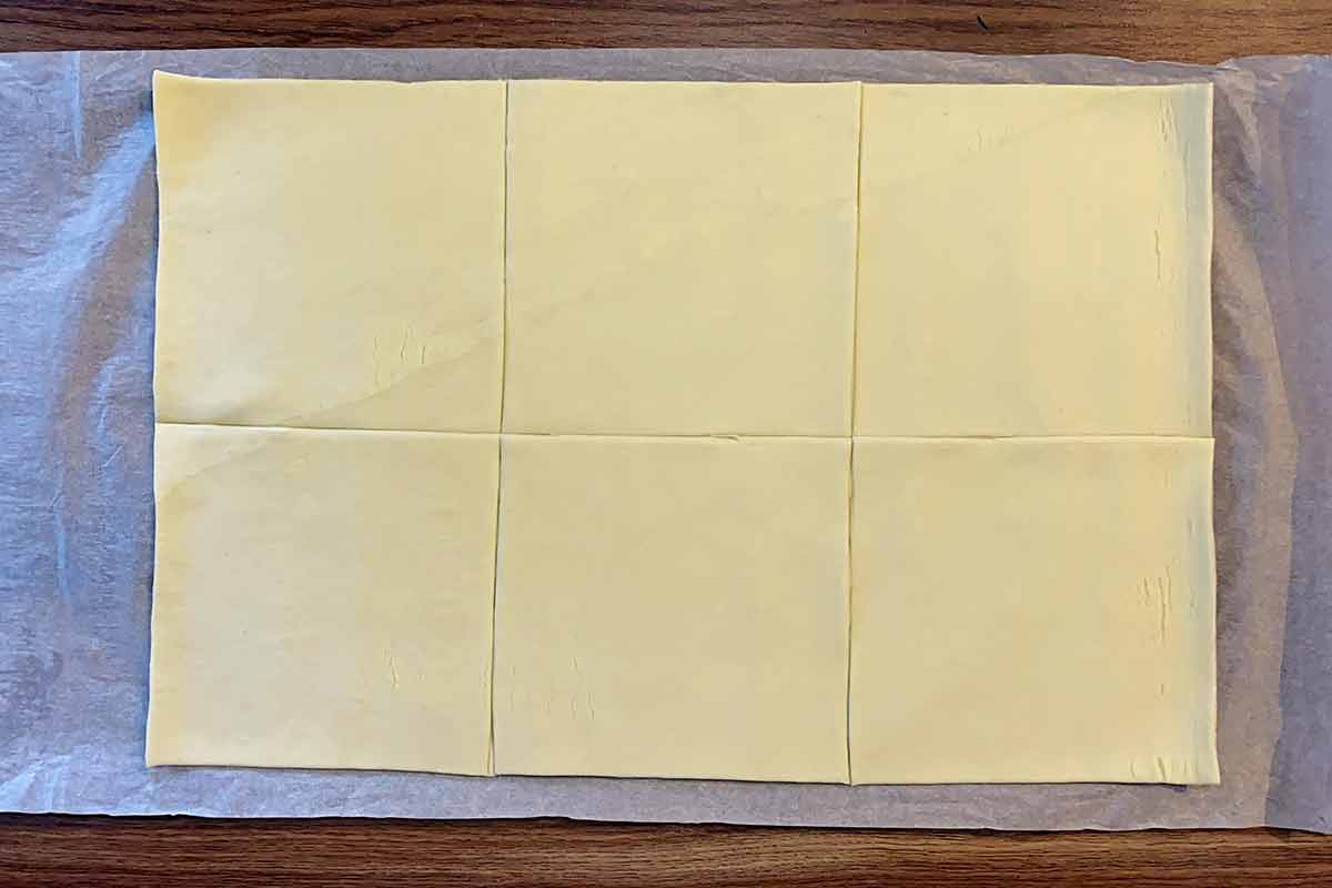 A sheet of uncooked puff pastry cut into six equal squared.