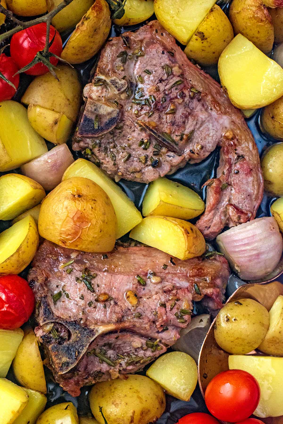 Two baked lamb chops surrounded by roasted new potato quarters.